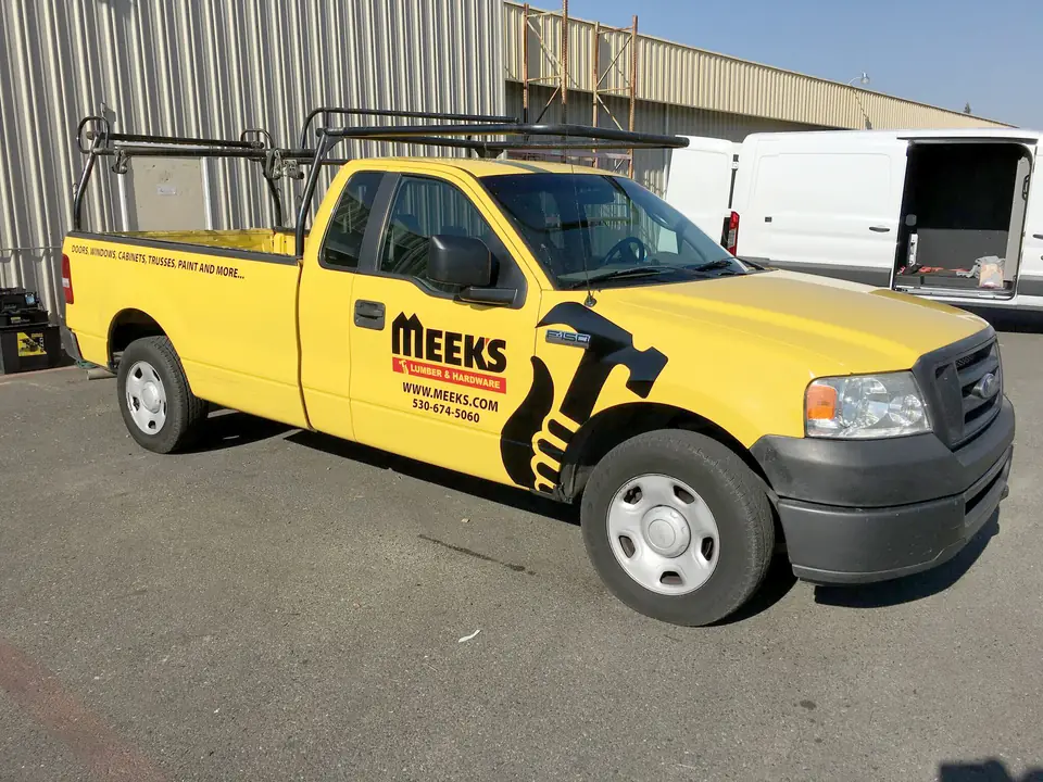 Yellow Meeks Lumber & Hardware pickup with logo graphics